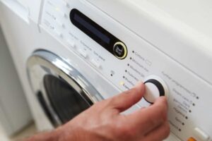 Mani che utilizzano la manopola della lavatrice
