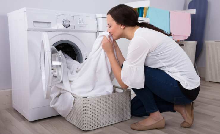 Donna annusa il bucato appena uscitodalla lavatrice