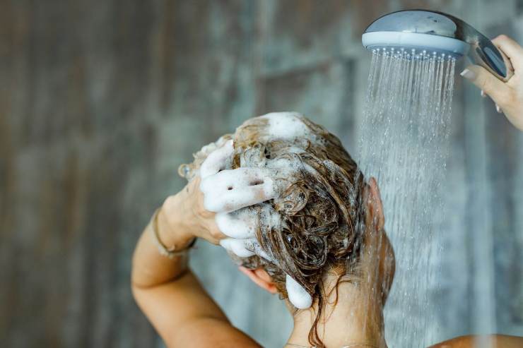 donna che lava i capelli sotto la doccia