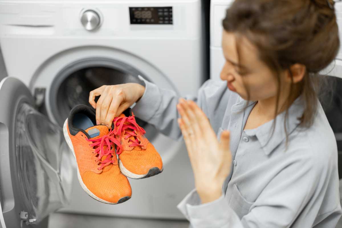 Donna tiene in mano delle scarpe sporche