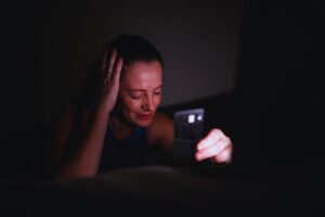 Donna in lacrime sul letto con carta di credito in mano