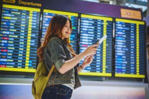 Ragazza in aeroporto che controlla il biglietto sullo smartphone