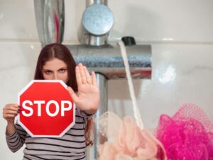 calcare nella doccia e donna con cartello stop