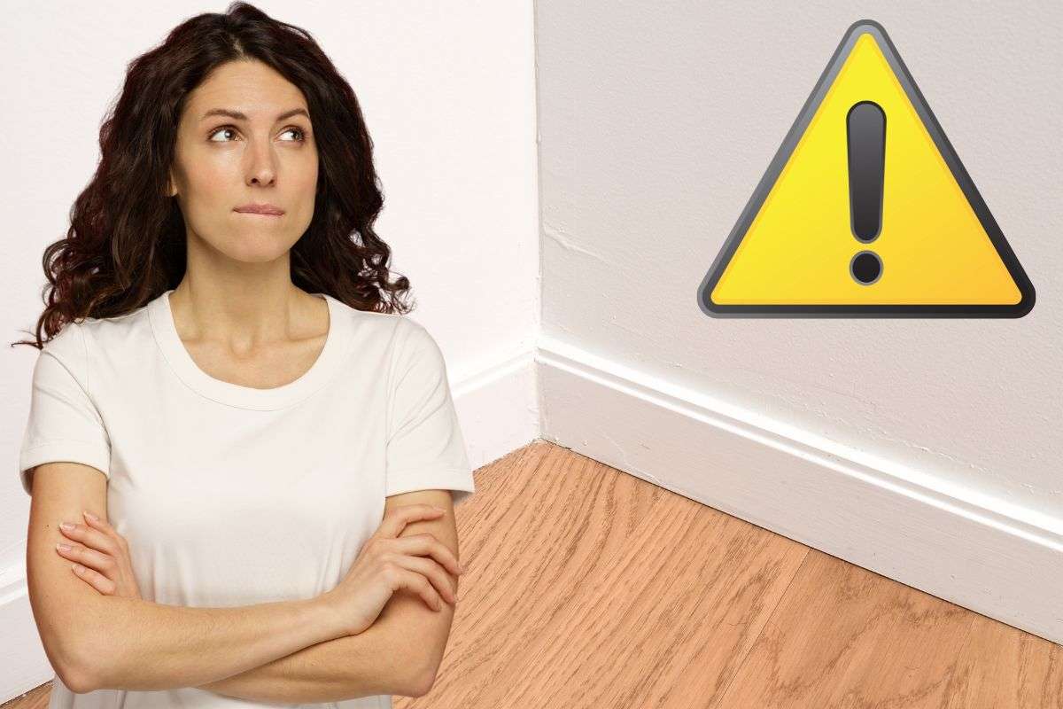 Angolo di casa, donna dubbiosa e triangolo giallo per attenzione