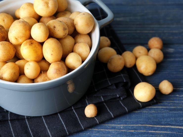 mucchio di patate novelle in una pentola su un tavolo di legno