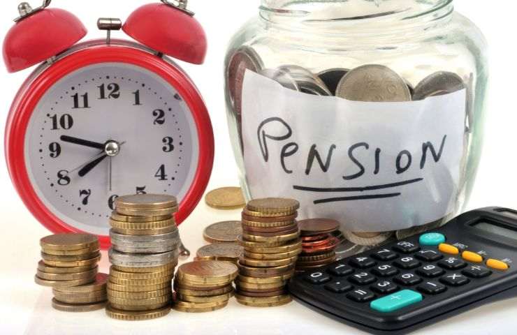 barattolo di vetro con scritta pensioni e soldi, monete su tavolo, calcolatrice e sveglia