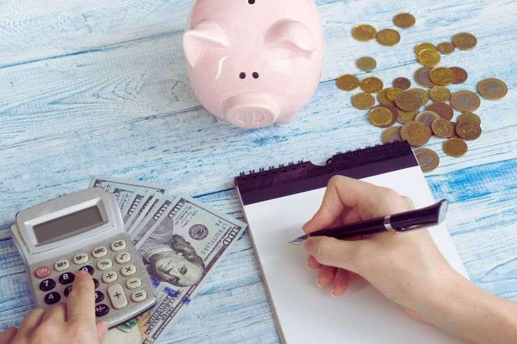 Euro, salvadanaio e persona che scrive con calcolatrice