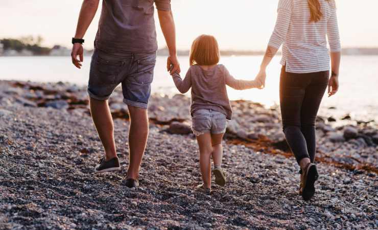 famiglia che si tiene per mano sulla spiaggia