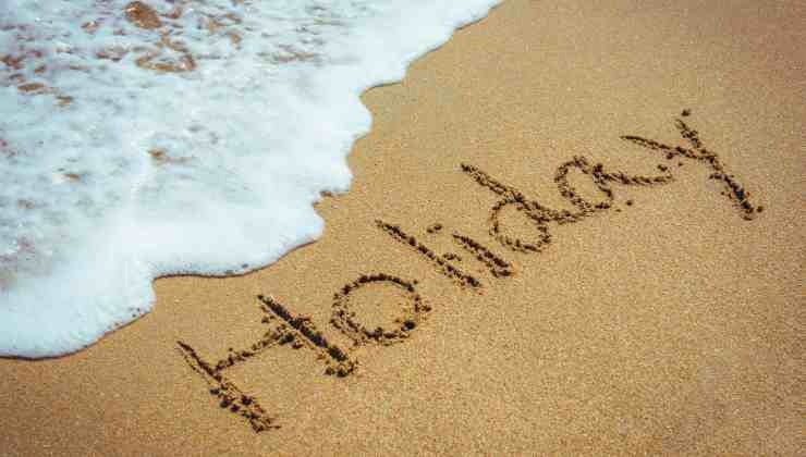 scritta holiday su sabbia e mare