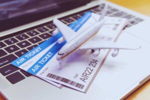 Biglietti e modellino aereo poggiati su tastiera di un portatile