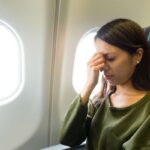 Donna con mano sul viso in aereo