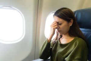 Donna con mano sul viso in aereo