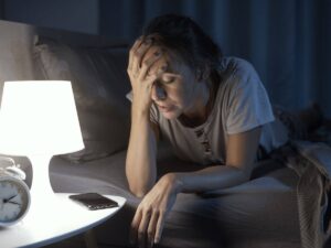 Donna che non dorme con mano sulla fronte e luce accesa
