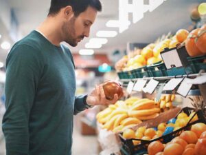 Uomo al supermercato che guarda la frutta