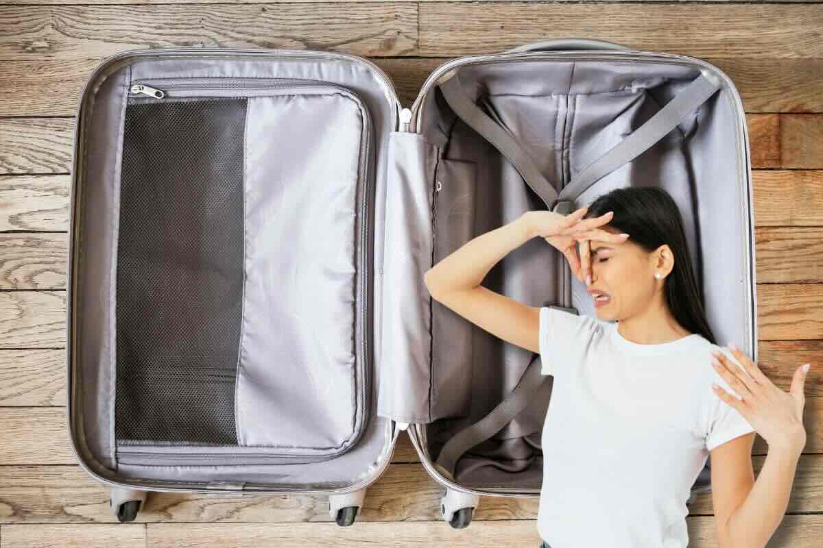 Donna si tappa naso, sul fondo valigia aperta vuota